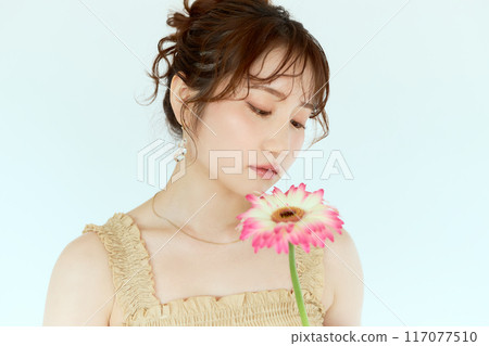 Portrait of a woman holding a gerbera 117077510