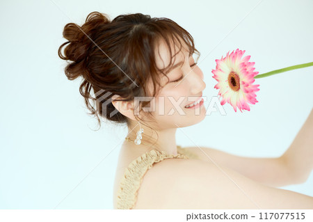Portrait of a woman holding a gerbera Portrait of a woman holding a gerbera 117077515