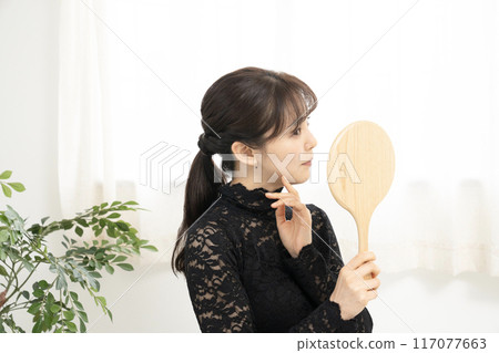 A woman wearing black lace clothes looking in the mirror A woman wearing black lace clothes looking in the mirror 117077663