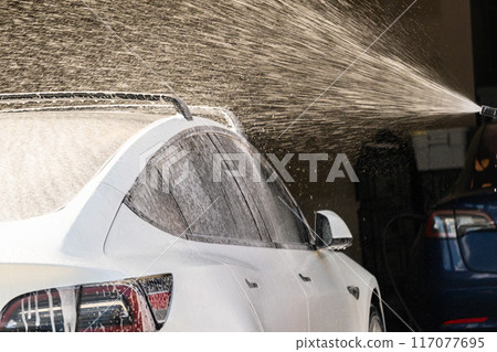 Efficiently cleaning an electric car in the comfort of a suburban driveway, combining eco-consciousness with practicality. 117077695
