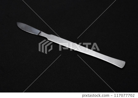A scalpel on a black background. A medical instrument. A scalpel on a black background. A medical instrument. 117077702