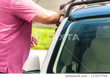 Efficiently cleaning an electric car in the comfort of a suburban driveway, combining eco-consciousness with practicality. Efficiently cleaning an electric car in the comfort of a suburban driveway, combining eco-consciousness with practicality. 117077704