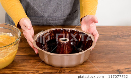 Carefully greasing a bundt cake pan in preparation for baking a delicious gingerbread bundt cake with caramel frosting. 117077732