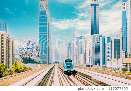 Monorail Subway train rides among glass skyscrapers in Dubai. Traffic on street in Dubai. Museum of the Future in Dubai. Cityscape skyline. Urban background 117077895