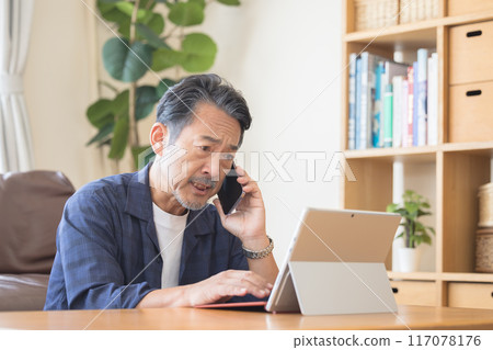 老人一邊用智慧型手機說話一邊操作電腦 117078176