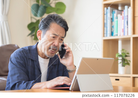 老人一邊用智慧型手機說話一邊操作電腦 老人一邊用智慧型手機說話一邊操作電腦 117078226