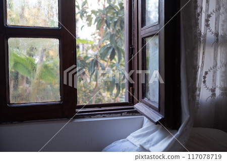 Bright morning sun in the open window through the curtains Bright morning sun in the open window through the curtains 117078719