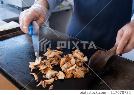 a chef cutting meat with a knife for a street food doner kebab or shawarma.  117078723