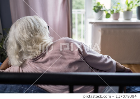 Resting smiling elderly woman reclining on a comfy sofa stretching, calm  117079394