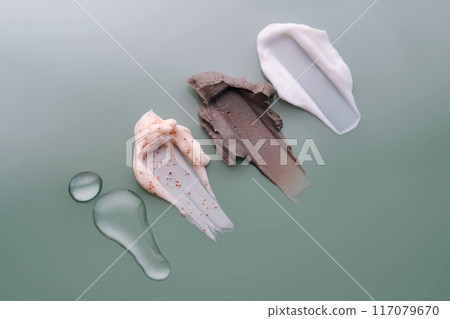 Textures of different cosmetic products on a green background. Textures of different cosmetic products on a green background. 117079670
