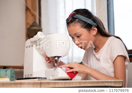 Girl using a sewing machine Girl using a sewing machine 117079976