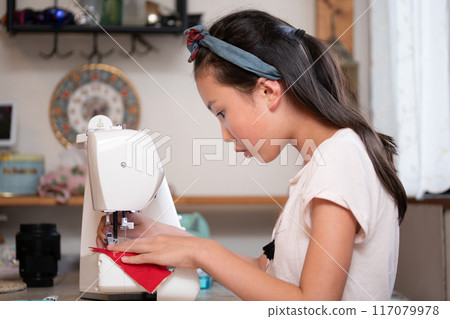 Girl using a sewing machine 117079978