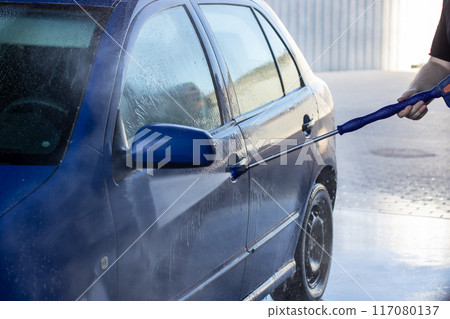 Man washing blue car with hose, keywords tire, wheel, vehicle Man washing blue car with hose, keywords tire, wheel, vehicle 117080137
