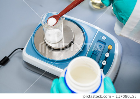 A woman utilizes laboratory balances to measure powder samples. 117080155