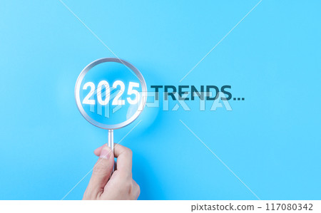 Trends 2025 year concept. Hand holding magnifying glass with 2025 trend searching bar for optimization 2025 business marketing trends and business plan in new year. Find information and new ideas. Trends 2025 year concept. Hand holding magnifying glass with 2025 trend searching bar for optimization 2025 business marketing trends and business plan in new year. Find information and new ideas. 117080342