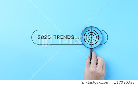 Trends 2025 year concept. Hand holding magnifying glass with 2025 trend searching bar for optimization 2025 business marketing trends and business plan in new year. Find information and new ideas. 117080353