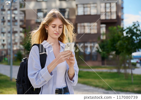 Walking young female using smartphone, modern city background 117080739