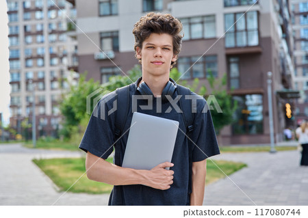 Portrait young male college student with backpack laptop, outdoor urban background 117080744
