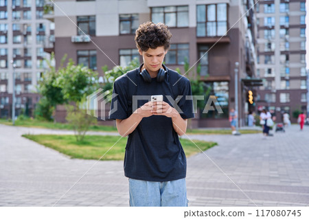Walking young guy using smartphone, modern city street background 117080745