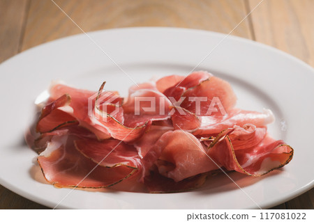 dried prosciutto ham on white plate 117081022