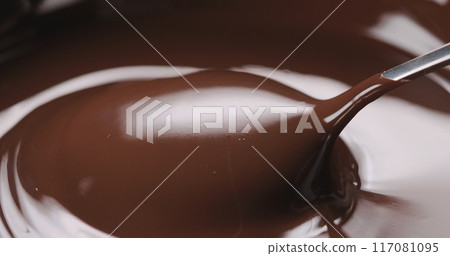 closeup pouring melted dark chocolate from spoon 117081095