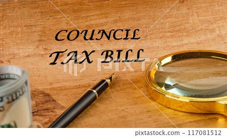 Business and finance concept. The inscription COUNCIL TAX BILL on papyrus in a composition with a magnifying glass, fountain pen and dollars without focus 117081512