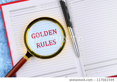 Conceptual golden rule symbol. Copy space. GOLDEN RULES words through a magnifying glass in an open business notebook. 117081594