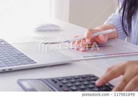 A woman filling out tax return documents 117081849