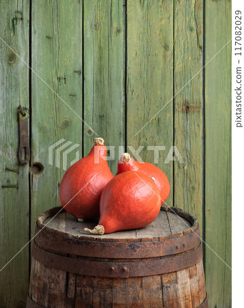Red Kuri Pumpkins on a Wooden Barrel 117082029