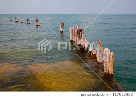 Serene Coastal Landscape with Weathered Wooden Posts in Clear Waters Serene Coastal Landscape with Weathered Wooden Posts in Clear Waters 117082408