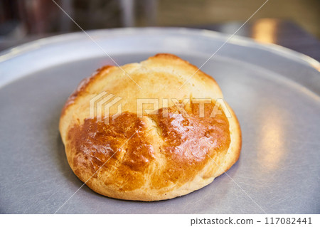 Golden Brioche Bun on Metallic Tray, Close-Up View 117082441