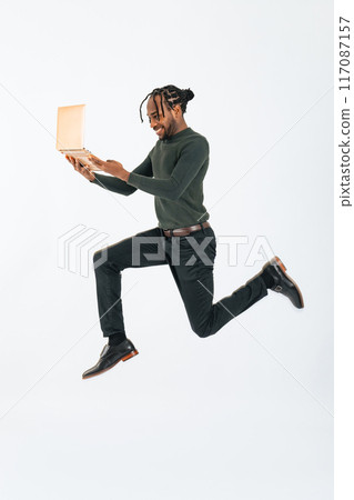 一名黑人男性商人看著筆記型電腦跳躍的全身照片 117087157