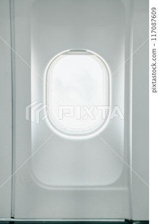 A minimalist photograph capturing the serene view through an airplane window, highlighting the clean white interior and soft natural light. A minimalist photograph capturing the serene view through an airplane window, highlighting the clean white interior and soft natural light. 117087609
