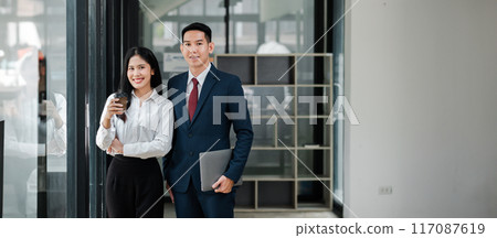 Confident business professionals standing in a modern office environment, showcasing teamwork and professionalism. Confident business professionals standing in a modern office environment, showcasing teamwork and professionalism. 117087619