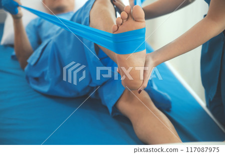 Physical therapists work with patients in close-up clinics. The concept of rehabilitation of physical health, the doctor gives advice to the patient. Ankle problems and muscle injuries Physical therapists work with patients in close-up clinics. The concept of rehabilitation of physical health, the doctor gives advice to the patient. Ankle problems and muscle injuries 117087975