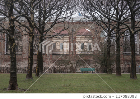 Green bench made wood and iron stand in the garden of the Munich Residenz with The Munich Residence in the background. 117088398