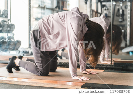 Young Asian woman stretching and doing flexibility exercises at the gym 117088708