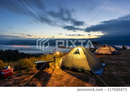 Tourist tent on camping site on the meadow next to the foggy during sunset, Thailand. Beautiful sunset twilight sky 117088873