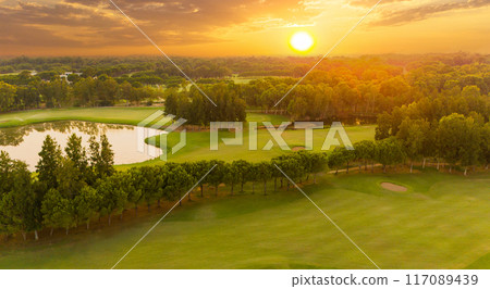 Golf course at sunset. Scenic panoramic aerial view of golf course at sunset with beautiful sky. Drone view Golf course at sunset. Scenic panoramic aerial view of golf course at sunset with beautiful sky. Drone view 117089439