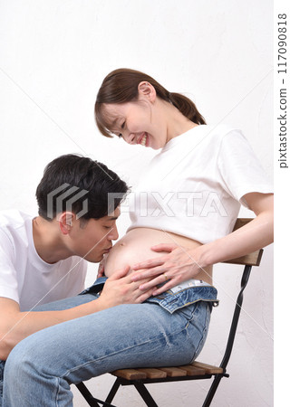 年輕的丈夫親吻他懷孕的妻子的大肚子 117090818