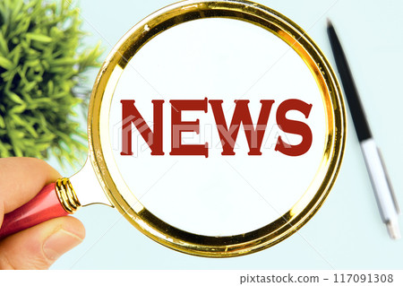 News word written through a magnifying glass in his hand on a white surface 117091308