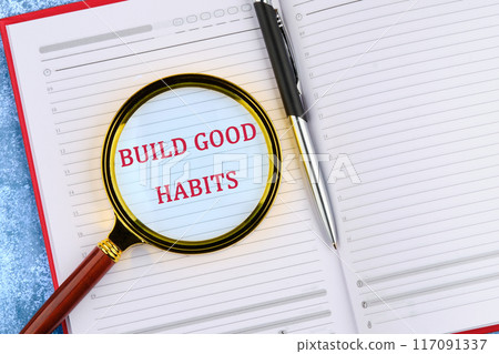 Healthy lifestyle and Healthy habits concept. Copy space. BUILD GOOD HABITS words through a magnifying glass in an open business notebook. 117091337