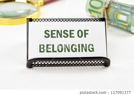 Business, sense of belonging concept. Copy space. SENSE OF BELONGING on a business card in a composition with Euro banknotes and a magnifying glass out of focus Business, sense of belonging concept. Copy space. SENSE OF BELONGING on a business card in a composition with Euro banknotes and a magnifying glass out of focus 117091377