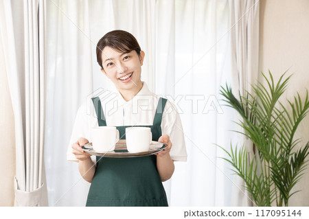 A female cafe staff member carrying coffee with a smile 117095144