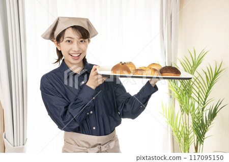 Female bakery staff holding freshly baked bread 117095150