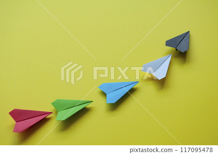 Black paper airplane leading the rest of the multicolored paper airplanes with customizable space for text Black paper airplane leading the rest of the multicolored paper airplanes with customizable space for text 117095478