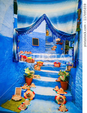 Chefchaouen, Morocco. Blue staircase and wall decorated with colourful flowerpots. Chefchaouen, Morocco. Blue staircase and wall decorated with colourful flowerpots. 117095859