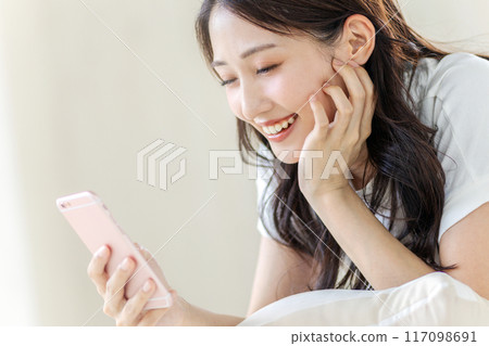 觀看有微笑的婦女一個智能手機 117098691