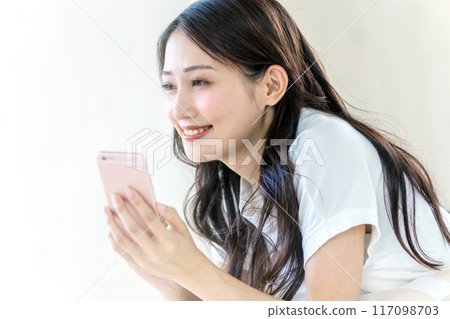觀看有微笑的婦女一個智能手機 117098703