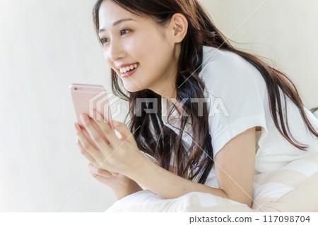 觀看有微笑的婦女一個智能手機 觀看有微笑的婦女一個智能手機 117098704
